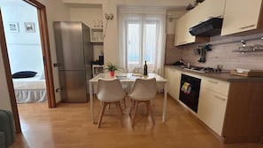 Une cuisine compacte comprenant un réfrigérateur, une table à manger avec des chaises, une fenêtre avec des rideaux et un petit four.