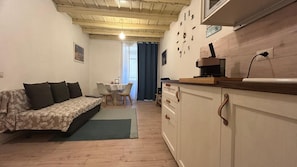 A compact living space with a sofa, a dining table, and a kitchenette. - Ankon Apartments Suite Don Gioia (Ancona)
