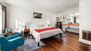 A bedroom with a bed, bedside tables, a desk, a chair, a window, and a radiator. - Jacobson's Cottages Cabin #3 (East Glacier Park)