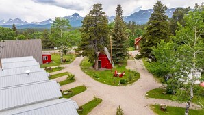 A rural property with a gravel path, red barn, and surrounding greenery. - Jacobson's Cottages Cabin # 5 (East Glacier Park)