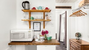 A compact kitchen with a microwave, wooden shelves, and a small refrigerator. - Jacobson's Cottages Cabin #10 (East Glacier Park)