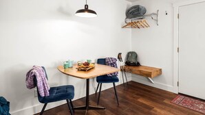 A compact room with a wooden table, two chairs, a hanging light fixture, a coat rack, and a door. - Jacobson's Cottages Cabin # 2 (East Glacier Park)