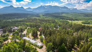 A mountainous landscape with a small settlement featuring several buildings, including a prominent red-roofed structure. - Jacobson's Cottages Cabin #11 (East Glacier Park)