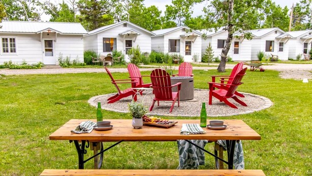 A picnic setup with a table and chairs in a grassy area with mobile homes in the background. - Jacobson's Cottages Cabin #11 (East Glacier Park)