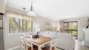A modern kitchen with a dining table, chairs, and a refrigerator. - 2BR Beach Villa with Balcony Pool Tennis Access (Hilton Head Island)
