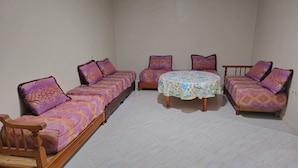 Ein Zimmer mit einer langen Couch, einem kleinen runden Tisch und einem Holzstuhl.