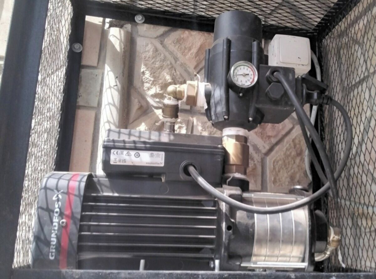 Un dispositif mécanique comprenant un moteur, un manomètre et une boîte de contrôle, qui fait probablement partie d’un système de chauffage.