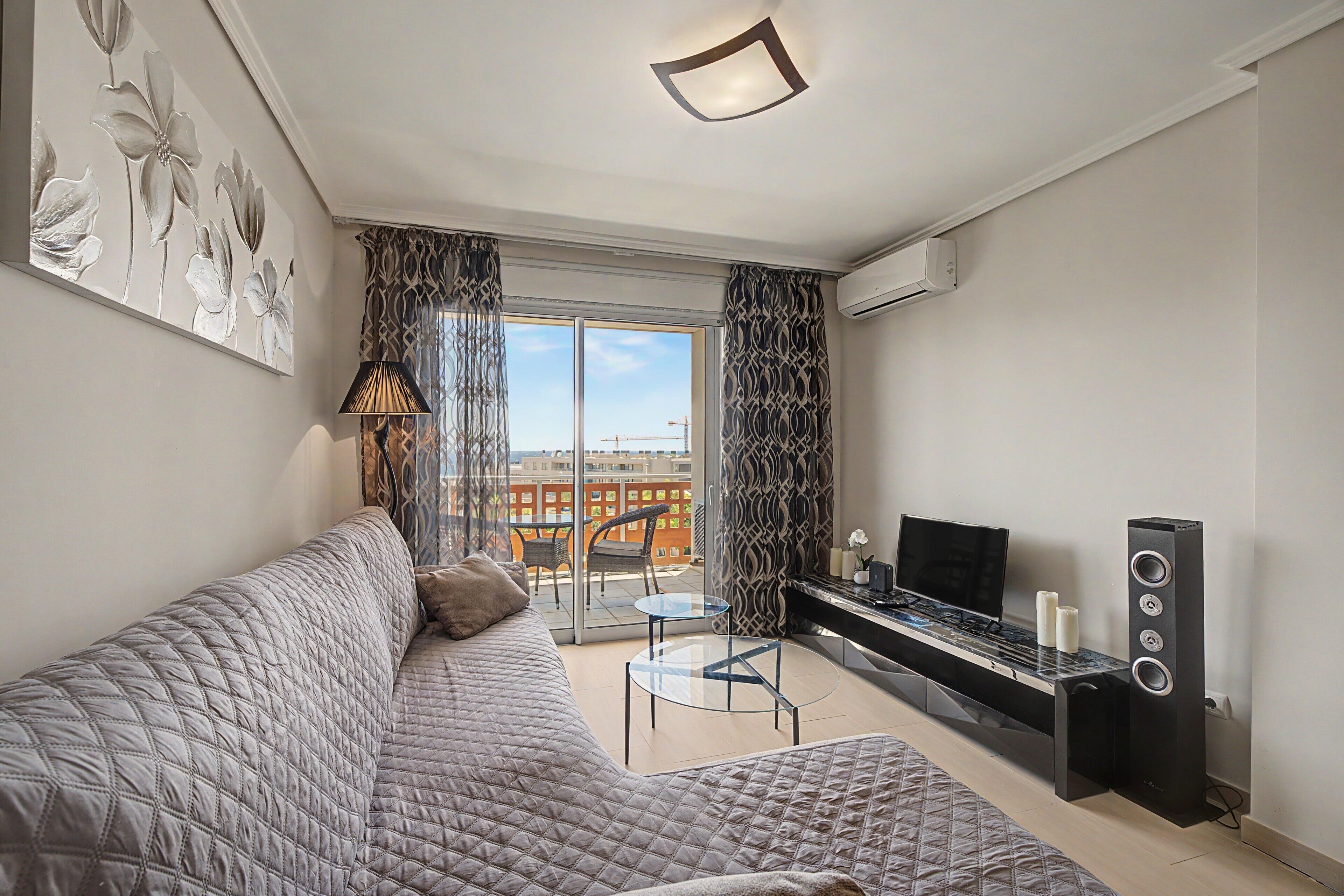 Una sala moderna con un sofá, una mesa de vidrio y un mueble para la televisión con parlantes.