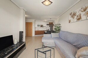A modern living room with a sectional sofa, a flat-screen TV, and a glass coffee table. - Vacation Apartment 'Vista Tejita' with Sea View, Wi-Fi and Air Conditioning (Granadilla)