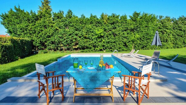 A poolside area with a table set for two, lounge chairs, and a clear view of the pool. - QUINTA DO MOSTEIRO:Charming refuge between history and nature (Ponte da Barca)