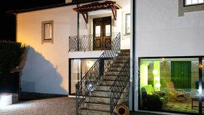 A two-story building with a staircase, a balcony, and a glass door leading to an outdoor seating area. - QUINTA DO MOSTEIRO:Charming refuge between history and nature (Ponte da Barca)