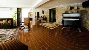 A spacious living room with a stone fireplace, a piano, and a green sofa. - QUINTA DO MOSTEIRO:Charming refuge between history and nature (Ponte da Barca)