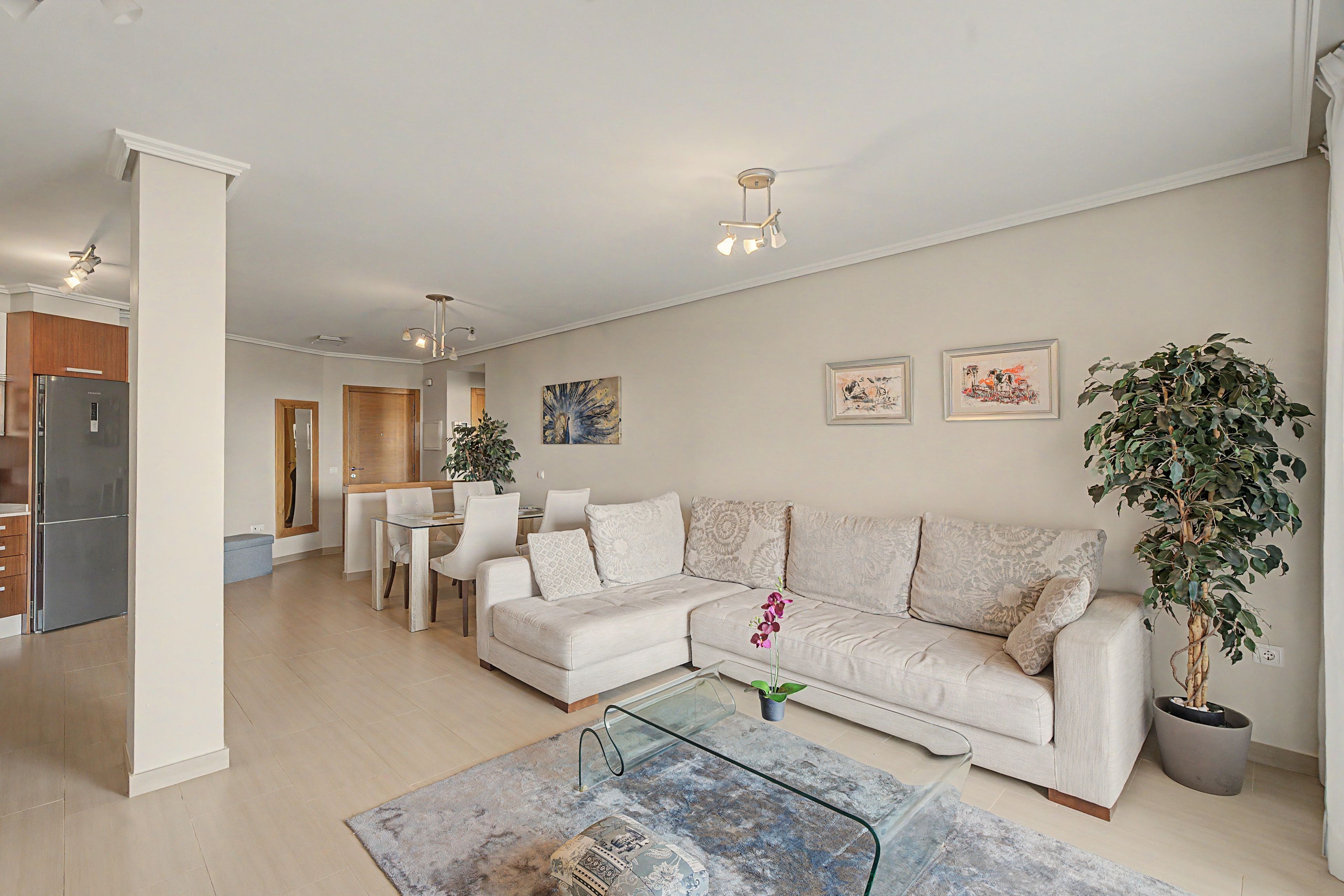 A modern living room with a sofa, coffee table, and a dining area with chairs.