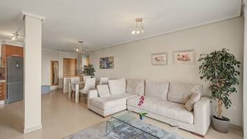 A modern living room with a sofa, coffee table, and a dining area with chairs.
