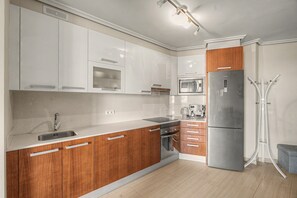 A modern kitchen with white cabinets, a stainless steel refrigerator, and a coffee maker.