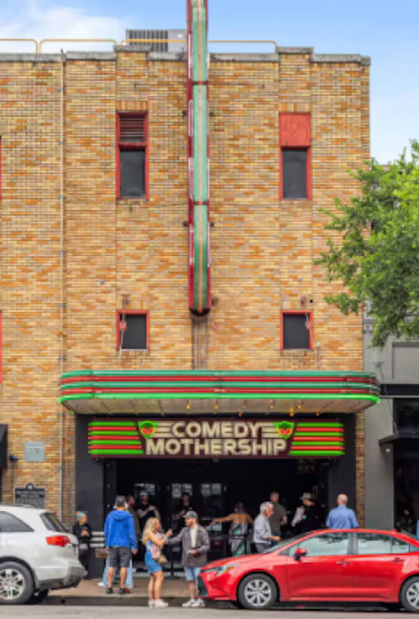 Un edificio de ladrillo con un letrero que dice 'COMEDY MOTHERSHIP'.