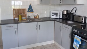 A kitchen with grey cabinets, a microwave, a coffee maker, and a stove. - Gite Barton 6 persons 500m from Utah Beach (Sainte-Marie-du-Mont)