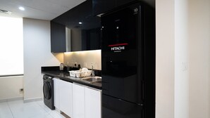 Une cuisine moderne avec un réfrigérateur noir, un lave-linge et un plan de travail sur lequel sont posés des ustensiles de cuisine.