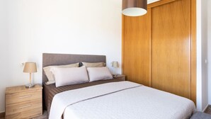 A bedroom with a bed, bedside tables, a lamp, and a wooden wardrobe.