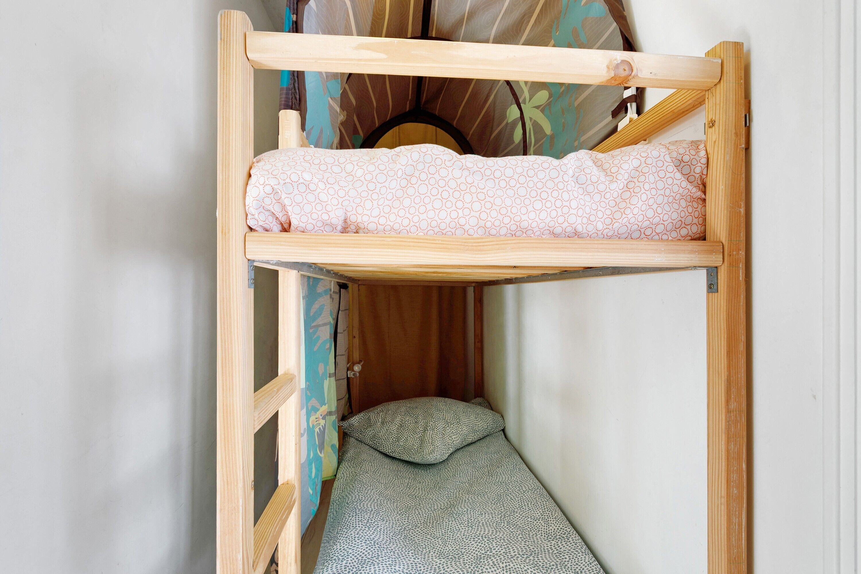 A bunk bed with a patterned mattress, a pillow, and a wooden frame.