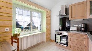 A kitchen with wooden cabinets, a window, a stove, and a sink. - Holiday Home “Le Sémaphore” – Just 50m from the Beach (Plougasnou)