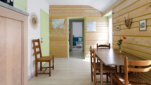 A dining area with wooden walls, a table, chairs, and a view into another room. - Holiday Home “Le Sémaphore” – Just 50m from the Beach (Plougasnou)