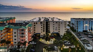 Ein Hotel mit Innenhof, mehreren Balkonen und Blick auf das Meer bei Sonnenuntergang.