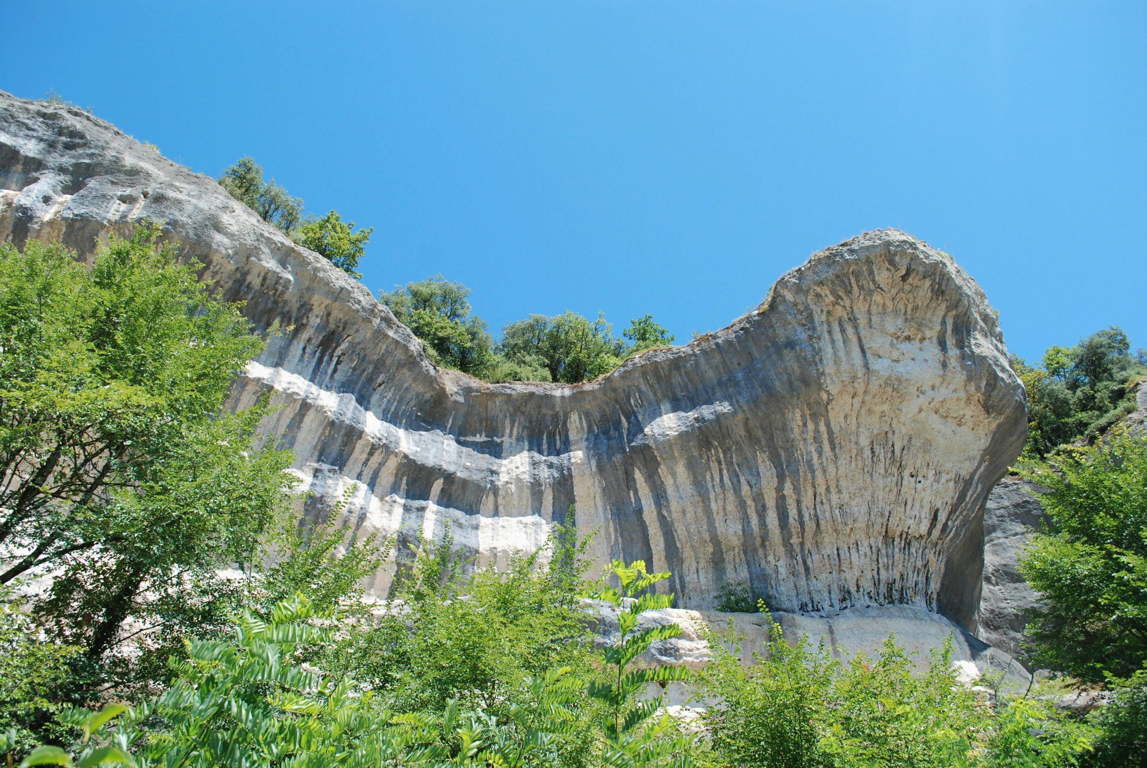 Une formation rocheuse naturelle caractérisée par des couches de sédiments et une végétation luxuriante environnante.