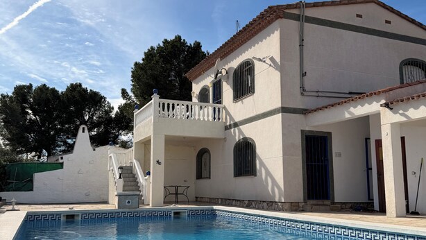 A poolside view of a white building with a tiled pool, a covered patio, and a staircase leading to an upper level. - Amarella Costa Dorada 1-bedroom apartment with pool (Les Tres Cales)