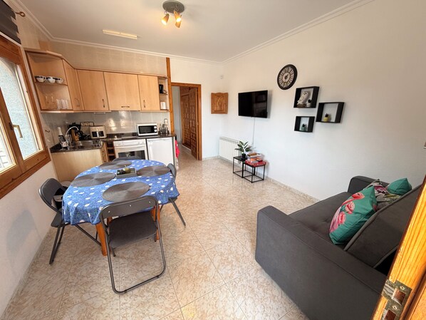 A compact living space with a dining area, kitchenette, and a sofa.