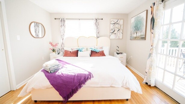 Una camera da letto con un letto, un comodino, una finestra con tende e un quadro appeso al muro.
