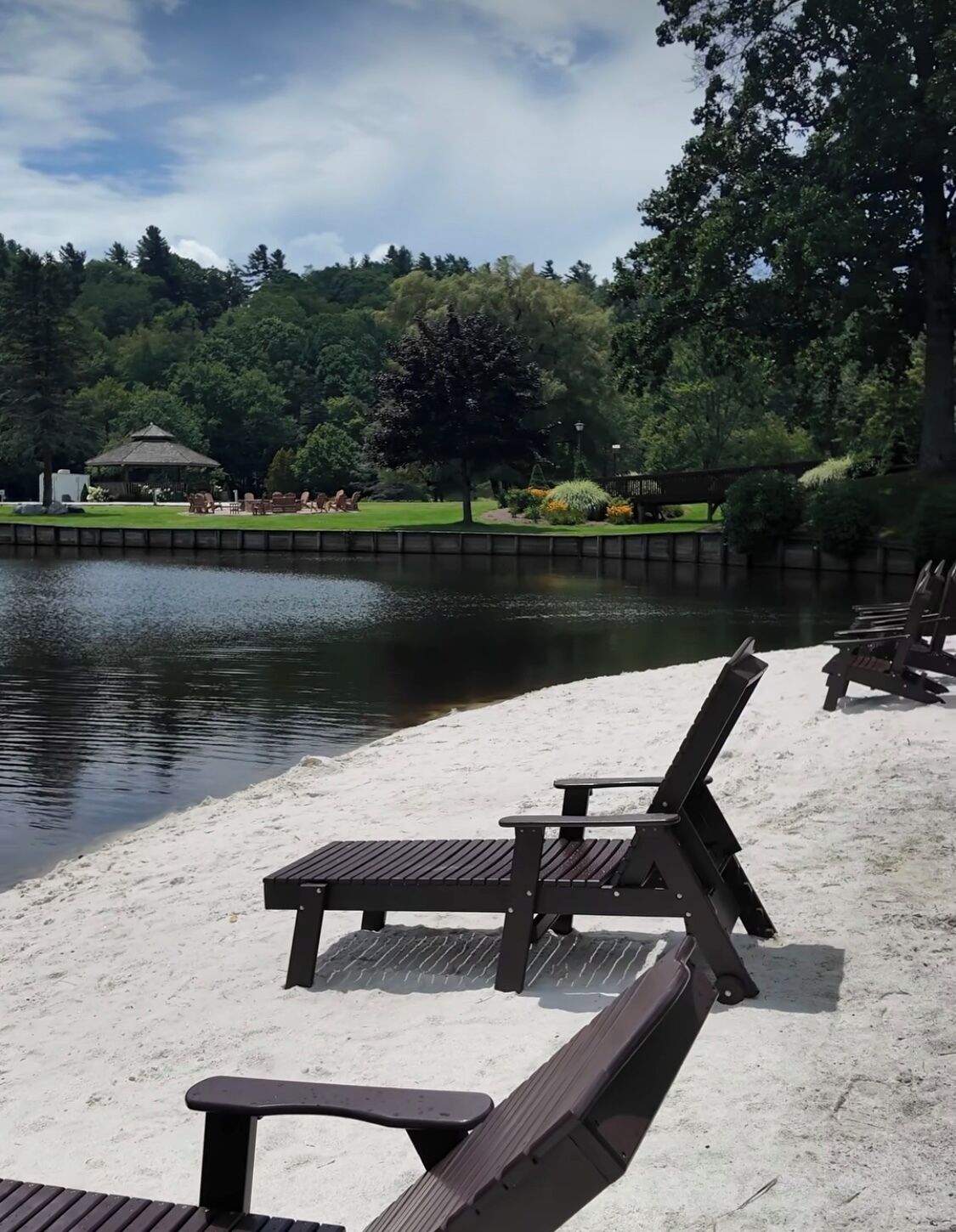 Een park aan het meer met houten banken en een kiosk.