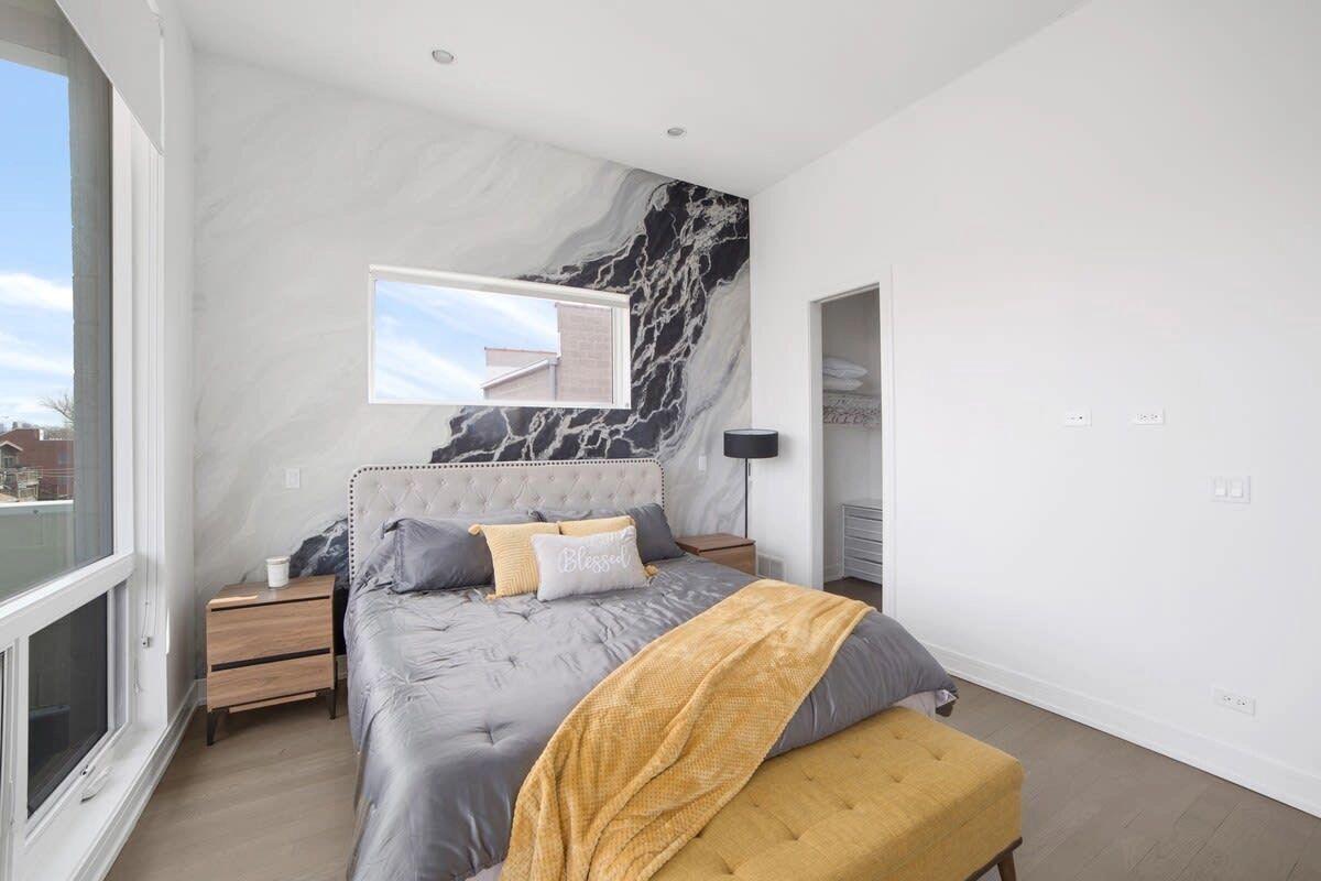 Ein modernes Schlafzimmer mit einem großen Bett, einem Fenster und einer Marmorwand.