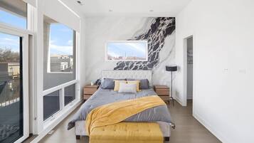 Quarto moderno com cama grande, vista para a cidade e parede de mármore.