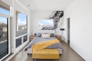 Een moderne slaapkamer met een groot bed, stadsgezicht en een marmeren wand.