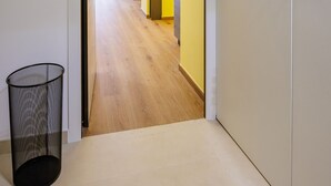 A hallway with a door leading to a room, a trash can, and a view of another room with a door. - Satriano Essence of Chiaia Flat (Naples)