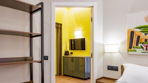 A hotel room with a bed, a desk with a lamp, a television, and a painting on the wall. - Satriano Essence of Chiaia Flat (Naples)