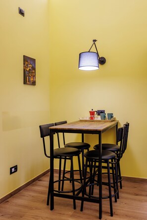 A dining area with a wooden table, black chairs, a hanging lamp, and a painting on the wall. - Satriano Essence of Chiaia Flat (Naples)