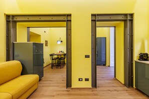 A modern interior with a yellow sofa, a dining area, and a kitchen. - Satriano Essence of Chiaia Flat (Naples)
