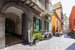 A narrow cobblestone street with historic buildings, a row of parked scooters, and a potted plant. - Satriano Essence of Chiaia Flat (Naples)