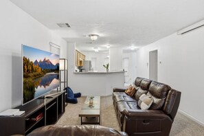 Una sala de estar con televisor de pantalla plana, sofá de cuero y una mesita de centro.