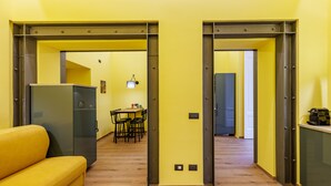 A modern interior with a yellow sofa, a dining area, and a kitchen. - Satriano Style Flat - Double apartment (Naples)