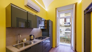 A modern kitchen with a sink, stove, and cabinets, leading to a balcony with a view. - Satriano Style Flat - Double apartment (Naples)