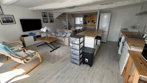 A modern living room with a sofa, coffee table, and a TV. There is a staircase leading to another level. - Cosy T3 apartment for 6 people in the heart of Paimpol (Paimpol)