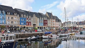 A marina with boats docked, a waterfront promenade, and colorful buildings with shops. - Cosy T3 apartment for 6 people in the heart of Paimpol (Paimpol)