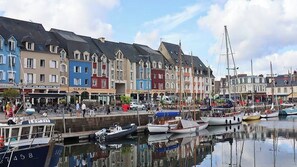 A marina with boats docked, a waterfront promenade, and colorful buildings with shops.