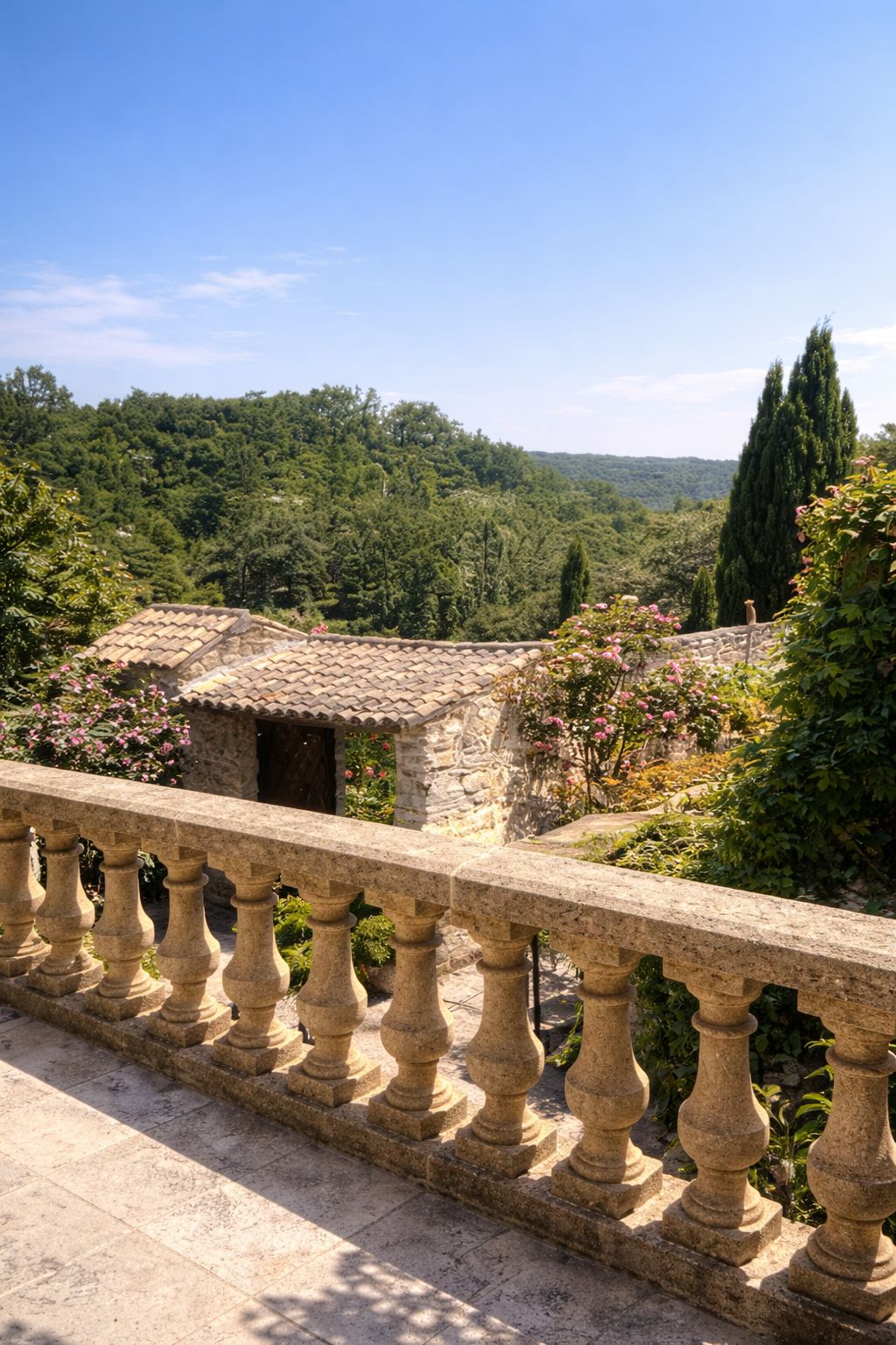 Une balustrade en pierre surplombe un jardin luxuriant, avec un bâtiment en pierre en arrière-plan.