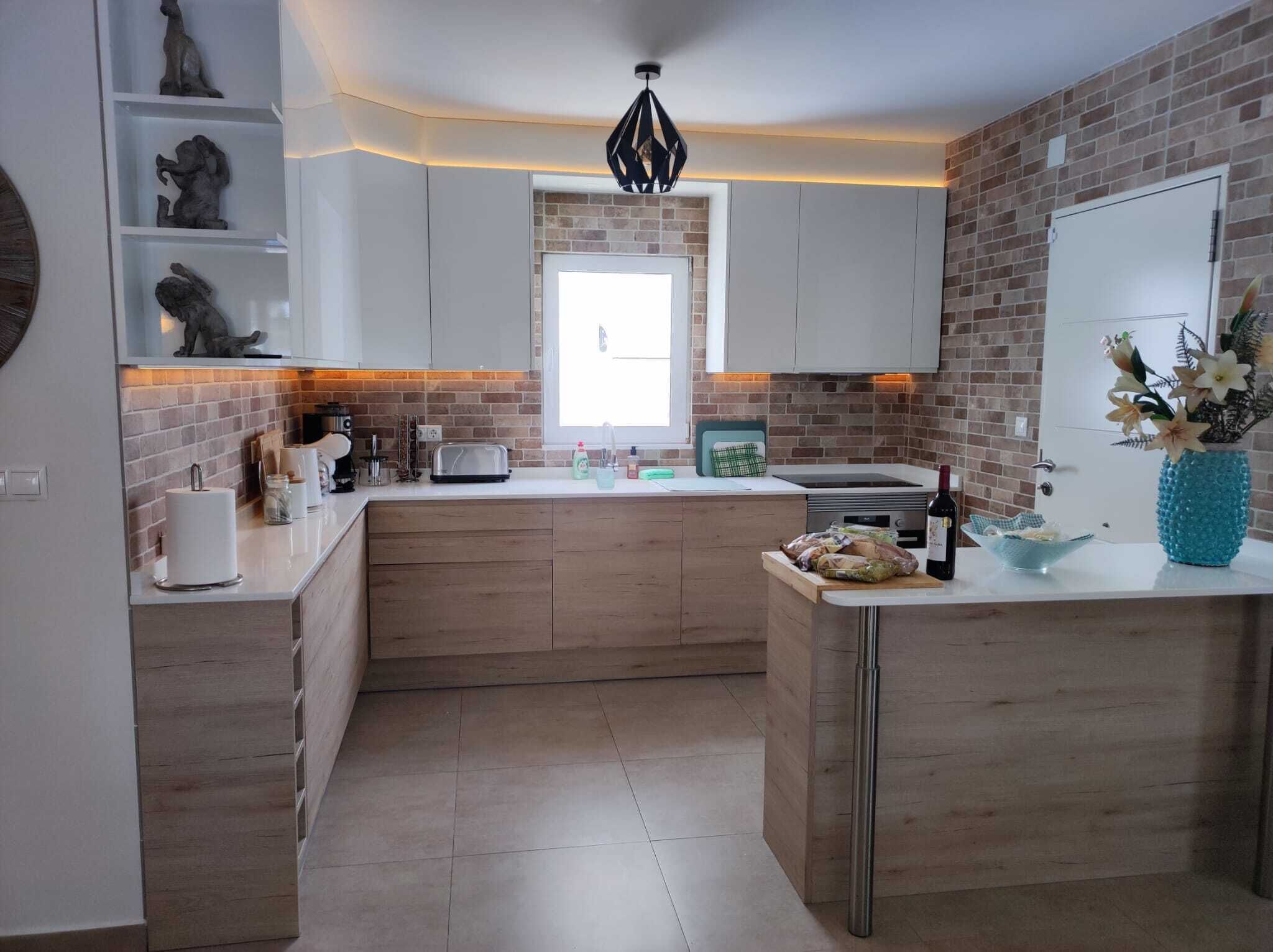 Una cocina moderna con armarios blancos, un salpicadero de ladrillo y una isla central.