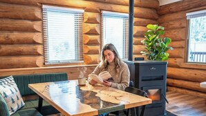 Ein gemütliches Blockhaus mit Holzwand, einem Esstisch, einem grünen Sofa und einem Blumentopf.