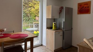 Eine kleine Küche mit Kühlschrank, einer Kaffeemaschine und einem Esstisch mit Stühlen.
